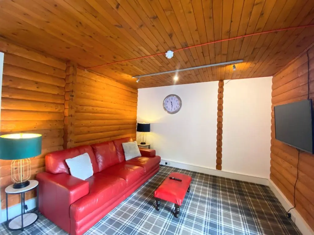 a living room with a red couch and a tv at Kaoglen Doe-Feature Bathroom-Cairngorms-Pets Allowed in Balnald