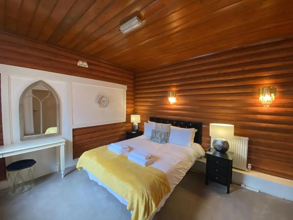 a bedroom with a large bed with wooden walls at Kaoglen-GrandSuite-Hot Tub-Pitlochry-Dunkeld-Pet Friendly in Balnald