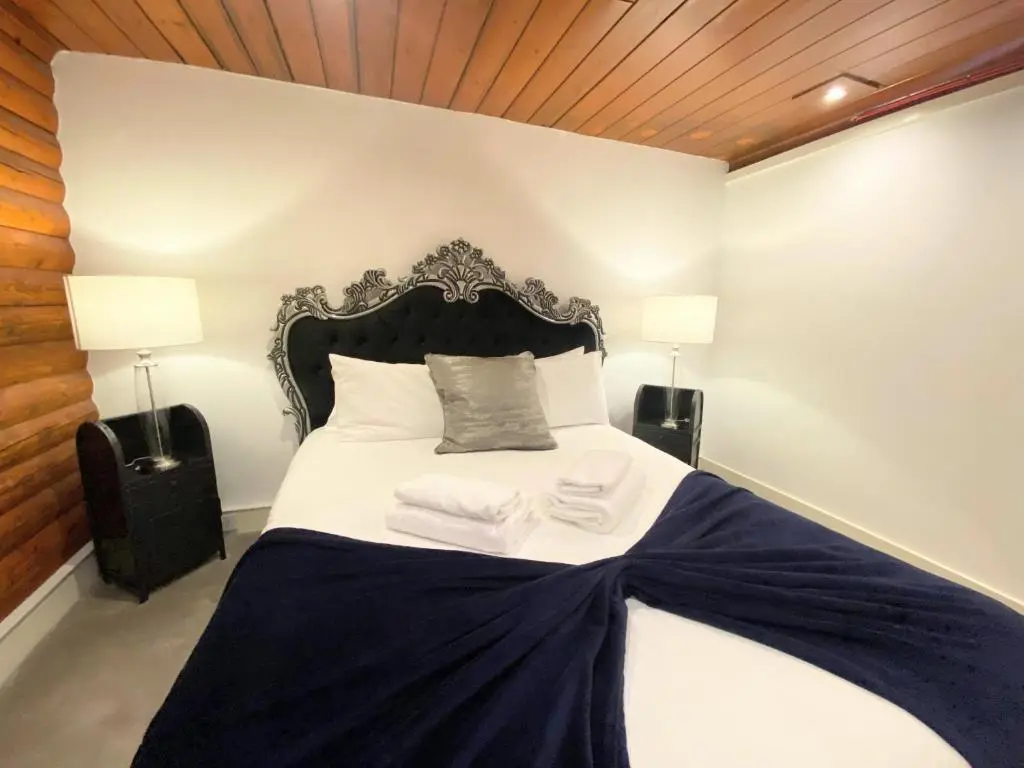 a bedroom with a black and white bed with two lamps at Kaoglen-GrandSuite-Hot Tub-Pitlochry-Dunkeld-Pet Friendly in Balnald