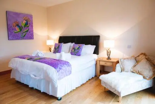 a bedroom with two beds and a chair at Clovenstone Lodges in Inverurie