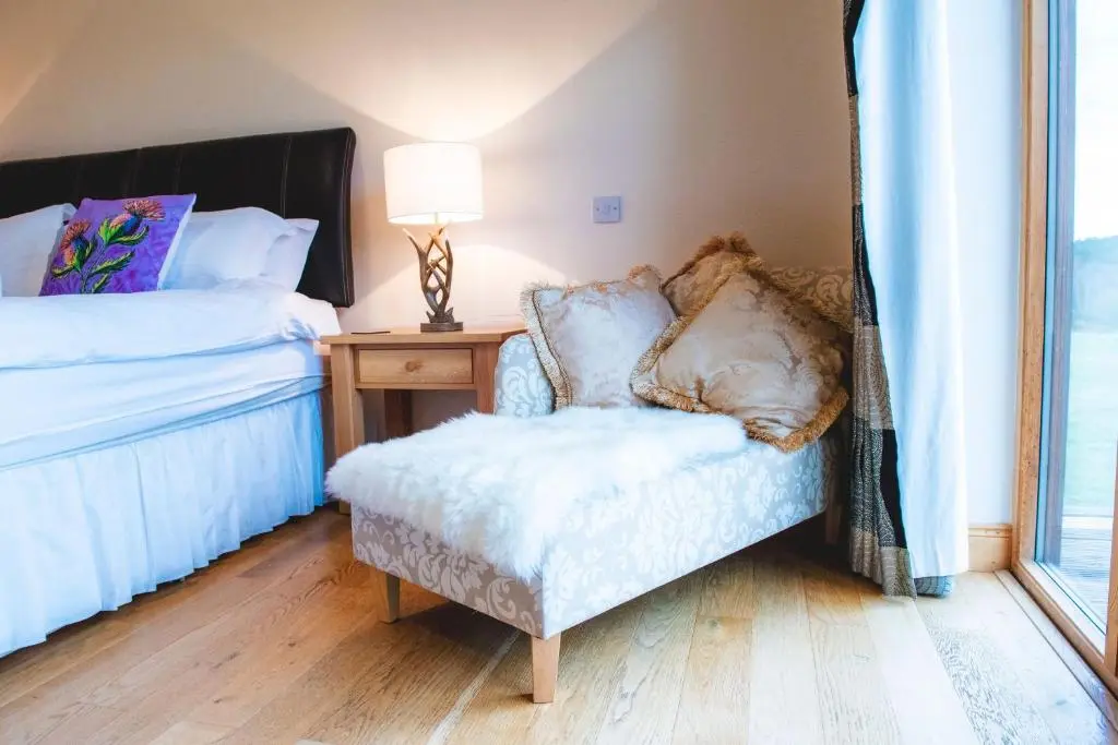 a bedroom with a chair and a bed and a window at Clovenstone Lodges in Inverurie