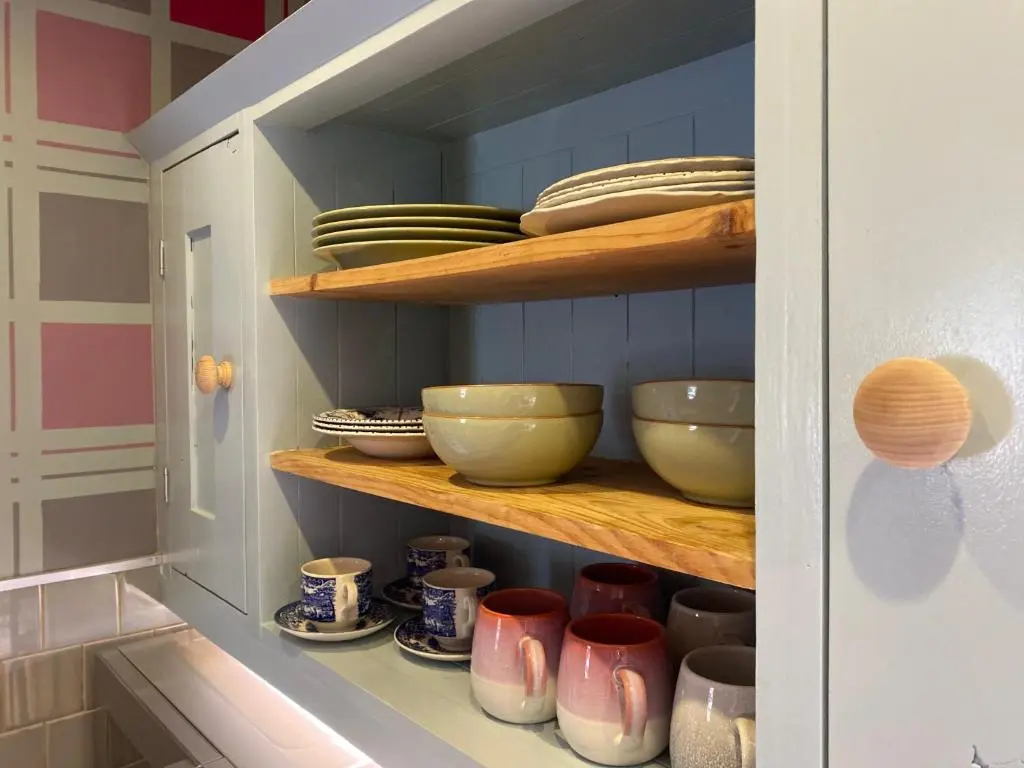 a cupboard filled with bowls and plates in a kitchen at Quirky Highland Cottage with Stunning Views in Wester Fearn