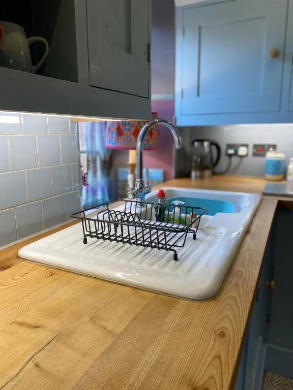 a kitchen counter with a drying rack on a sink at Quirky Highland Cottage with Stunning Views in Wester Fearn