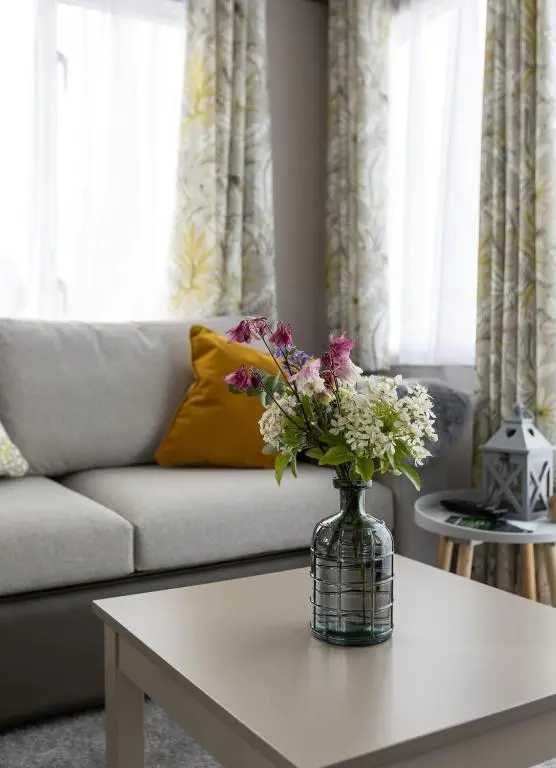 a vase of flowers on a table in a living room at The Beach Hut, Burghead in Burghead