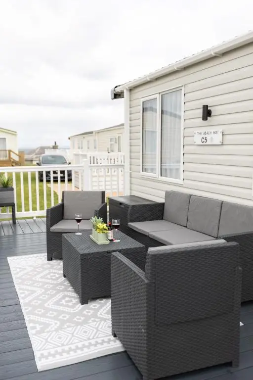 a patio with wicker furniture on a deck at The Beach Hut, Burghead in Burghead