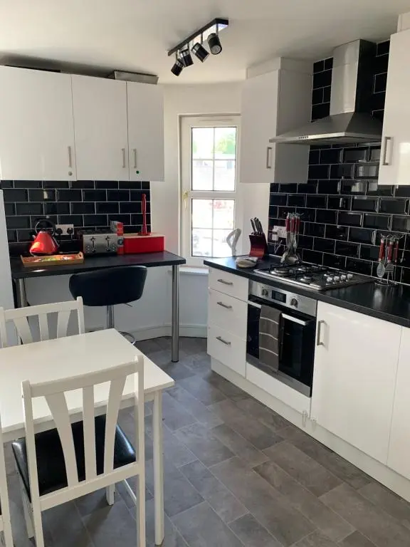 a kitchen with white cabinets and a stove and a table at Stylish apartment in the heart of Inverness in Inverness