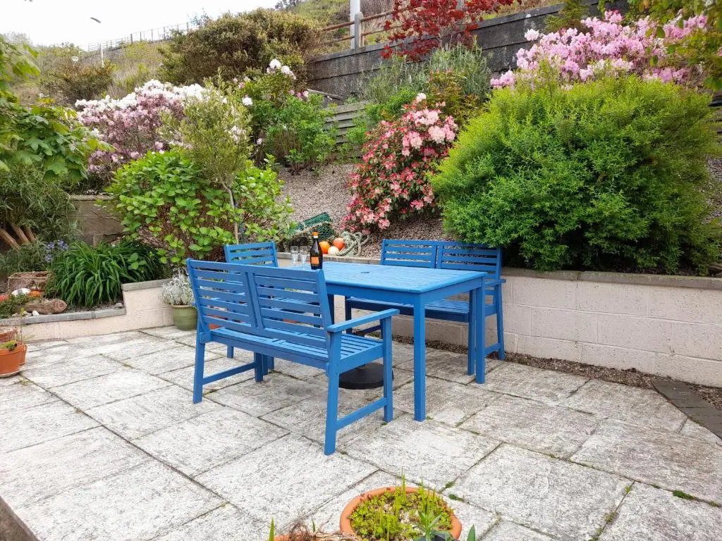 a blue table and chairs on a patio with flowers at Creel Cottage Seatown Cullen with Garden in Cullen