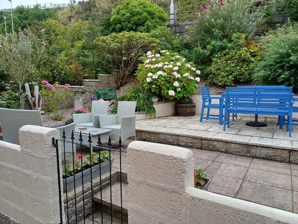 a patio with blue tables and chairs and flowers at Creel Cottage Seatown Cullen with Garden in Cullen