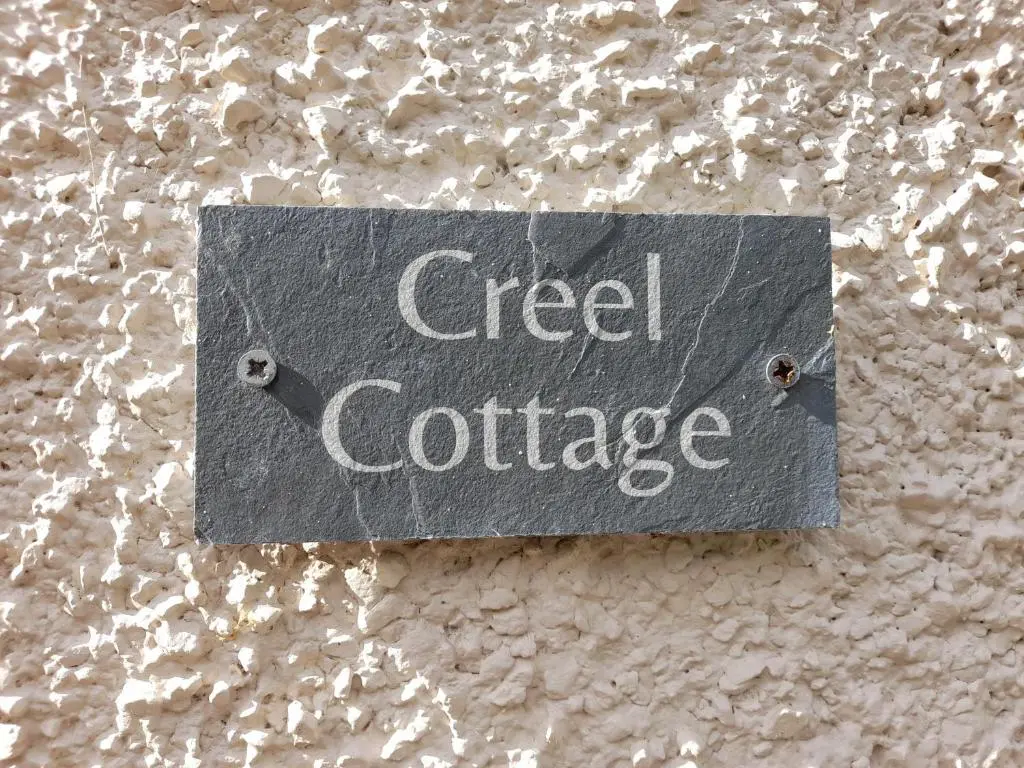 a sign that reads greed confidence hanging on a wall at Creel Cottage Seatown Cullen with Garden in Cullen