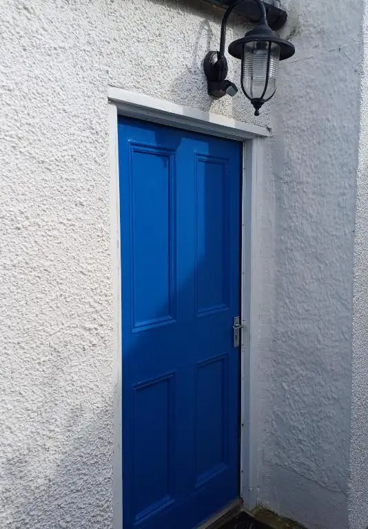 a blue door on the side of a white building at Creel Cottage Seatown Cullen with Garden in Cullen
