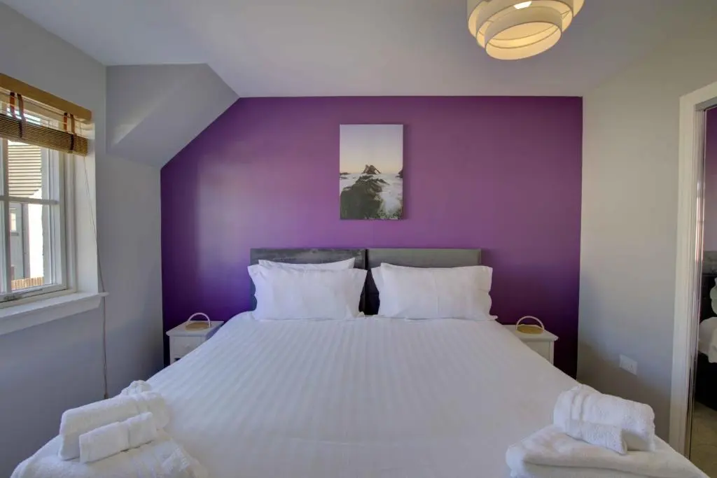 a purple bedroom with a large bed with white pillows at 3 Mackay Road, Dornoch in Dornoch