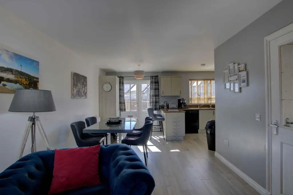 a living room and kitchen with a table and chairs at 3 Mackay Road, Dornoch in Dornoch