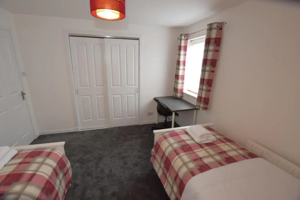 a bedroom with two beds and a table and a window at Silver Key Apartments III in Inverness