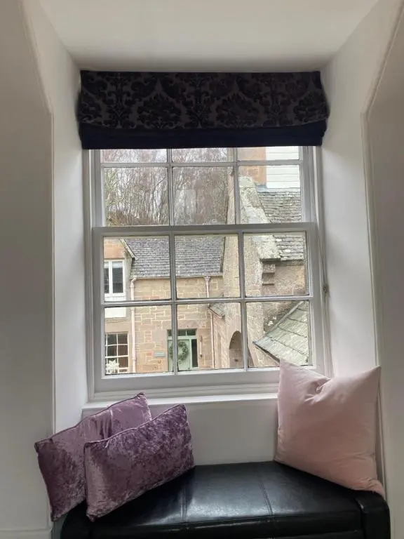 a window with a black leather couch in front at Brylach Steading in Aberlour