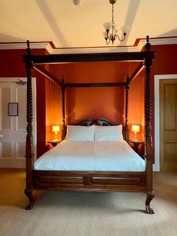 a bedroom with a bed with an orange wall at The Pines Guest House in Elgin
