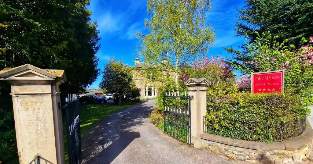 a gate to a house with a sign on it at The Pines Guest House in Elgin