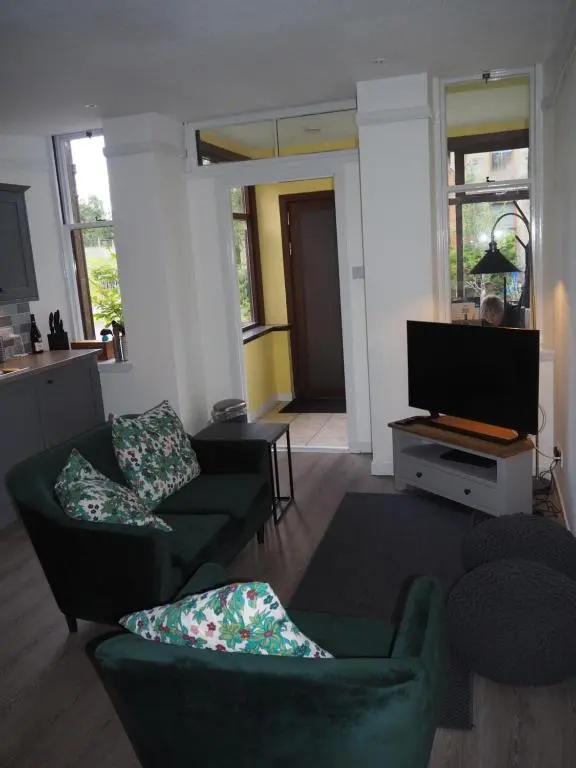 a living room with two couches and a flat screen tv at Uist Cottage in Kingussie