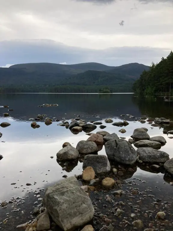 a group of rocks in the water on a lake at Uist Cottage in Kingussie