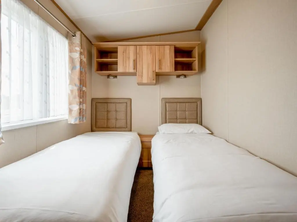 two beds in a small room with a window at Holiday Home Golf View by Interhome in Nairn