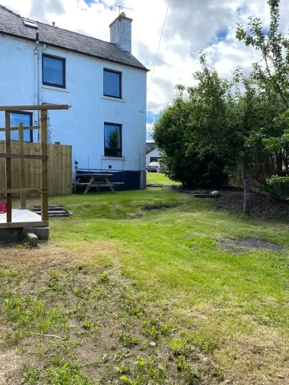 a white house with a yard with a yard at No 5 Newly refurbished 4 bedroom house in Cononbridge