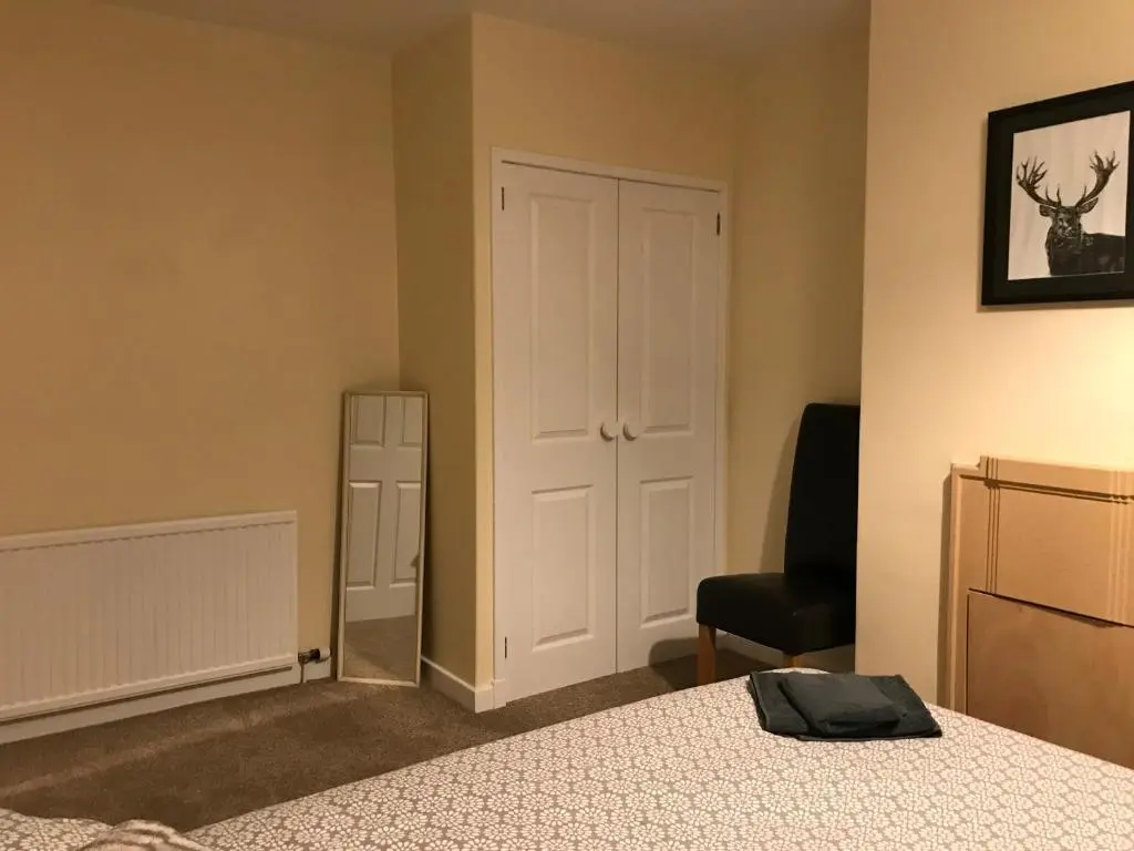 a bedroom with a bed and a chair and a door at No 5 Newly refurbished 4 bedroom house in Cononbridge