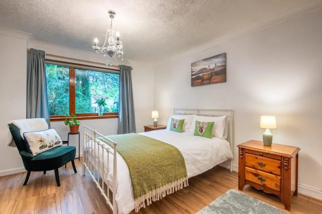 a bedroom with a bed and a chair and a window at Stylish Garden Flat Near Loch Ness in Drumnadrochit