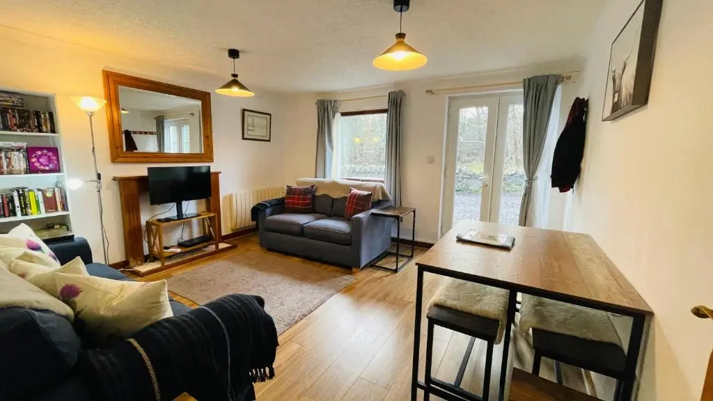 a living room with a couch and a table at Stylish Garden Flat Near Loch Ness in Drumnadrochit