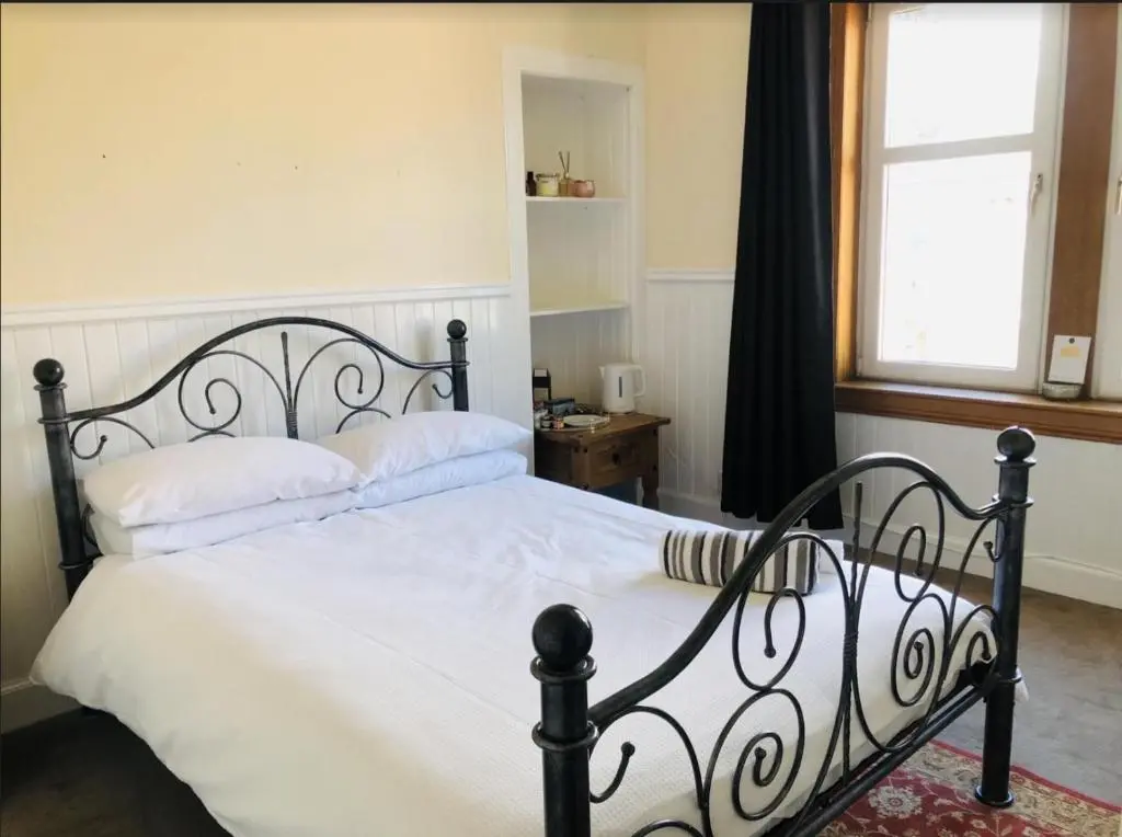 a bedroom with a bed with white sheets and a window at The Castle Front Nest in Inverness