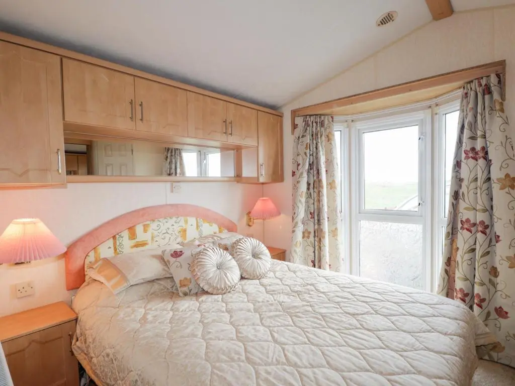 a bedroom with a large bed and a window at The Cabin in Lybster