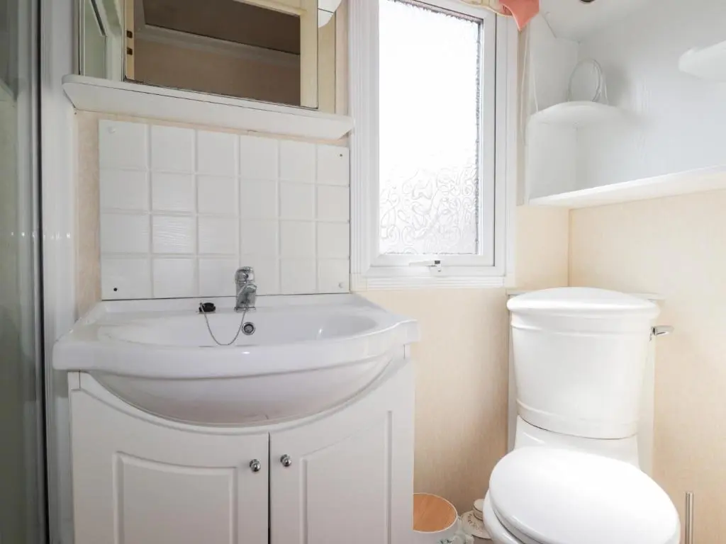 a bathroom with a white sink and a toilet at The Cabin in Lybster