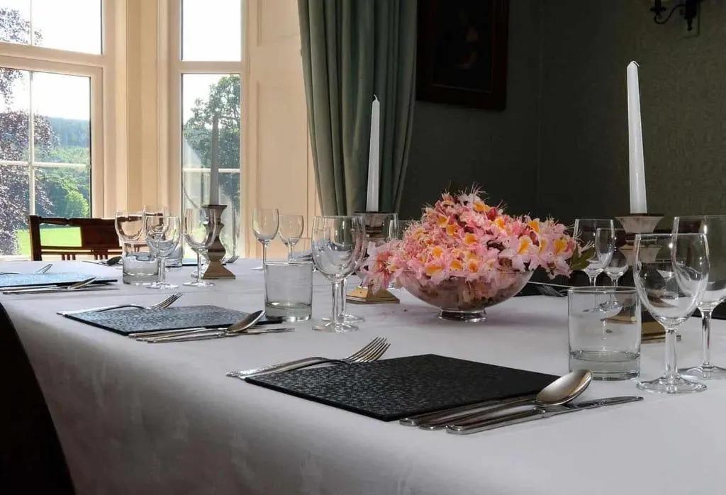 a white table with glasses and a vase of flowers at Mains of Orton in Fochabers