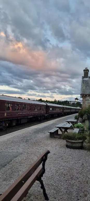 a bench sitting next to a train on the tracks at The Wee Hoose in Boat of Garten