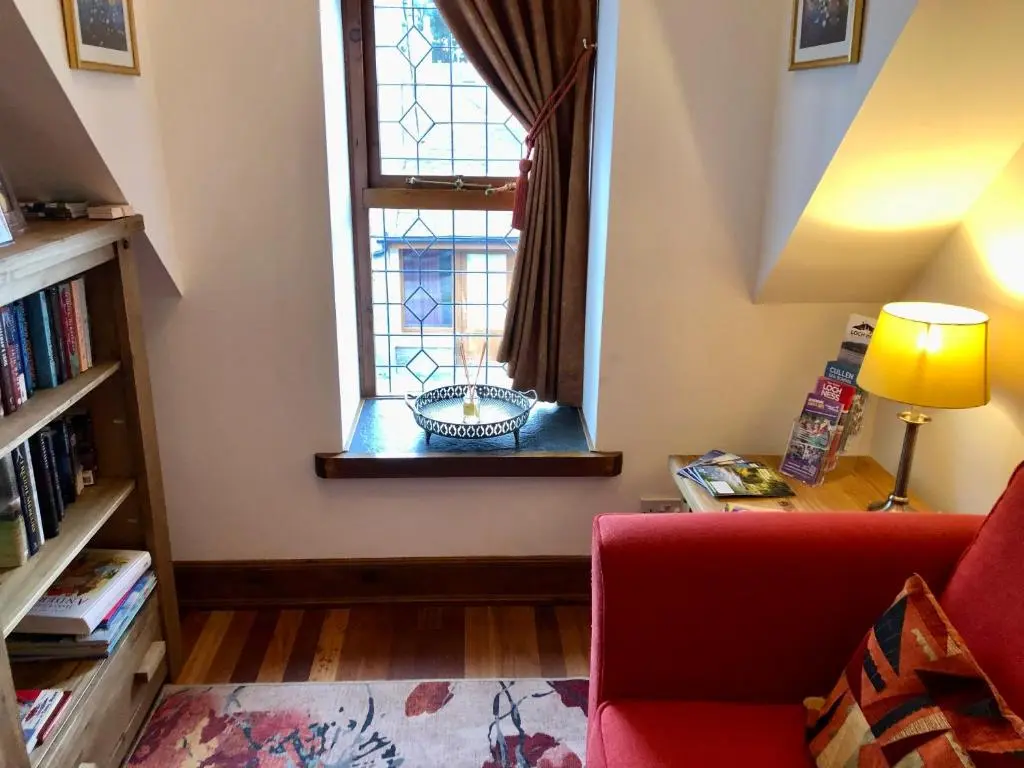 a living room with a red couch and a window at The Tower, Moray Firth Holiday Home in Kinloss