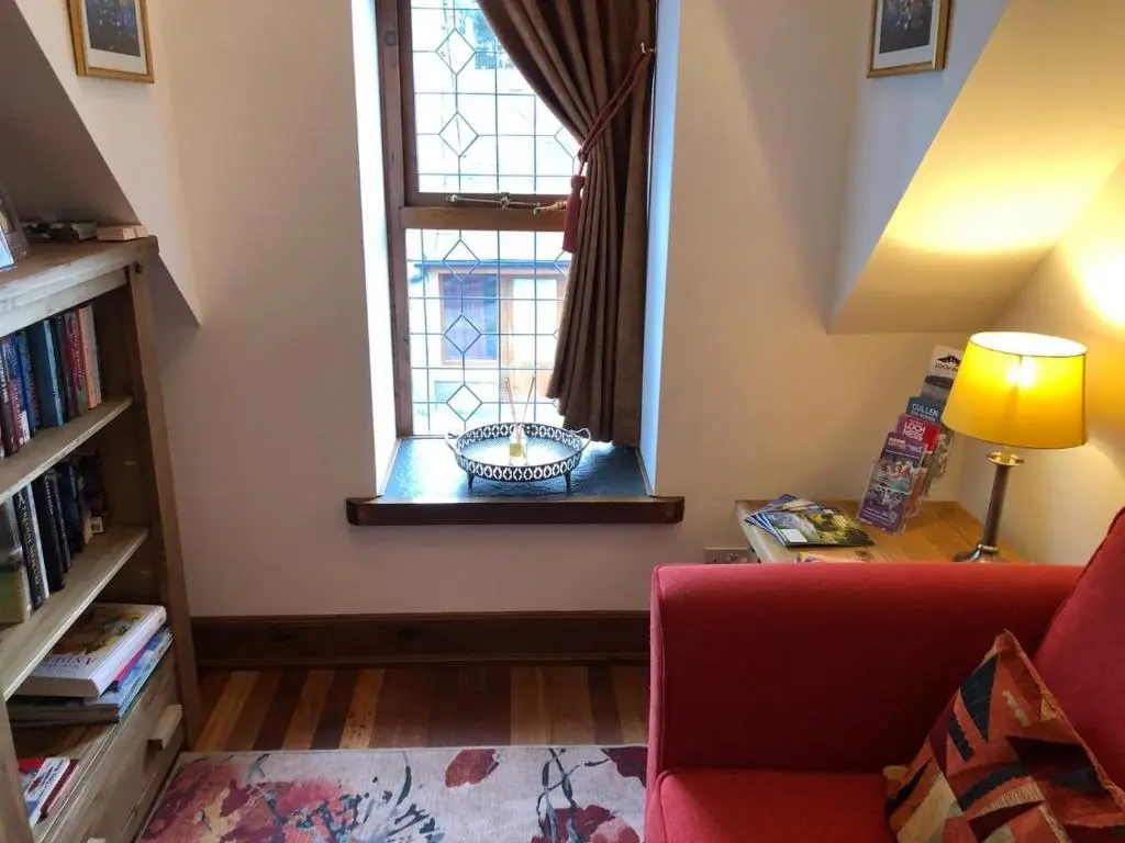 a living room with a red couch and a window at The Tower, Moray Firth Holiday Home in Kinloss