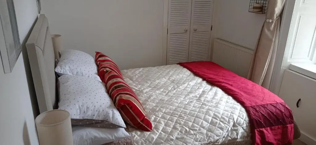 a bedroom with a bed with red and white pillows at Isla Way Stays in Keith