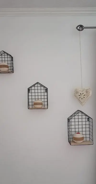 three bird cages hanging on a white wall at Isla Way Stays in Keith