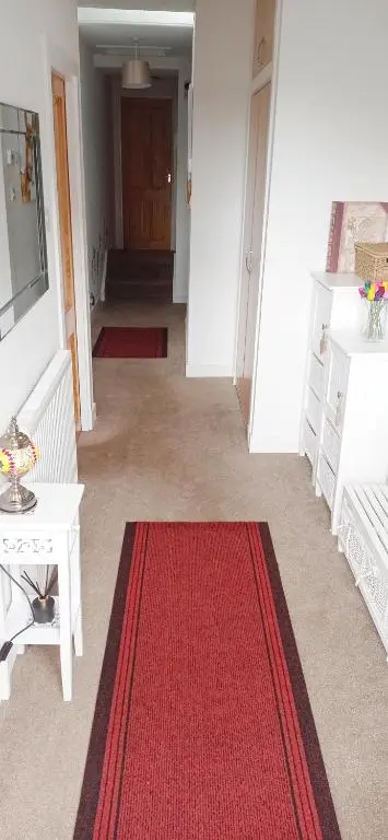 a hallway with a red rug and a white table at Isla Way Stays in Keith