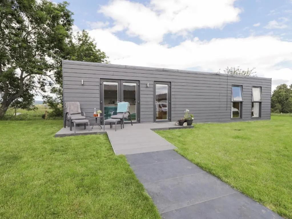 a small gray house with a patio and grass at Moss of Bourach in Aberlour