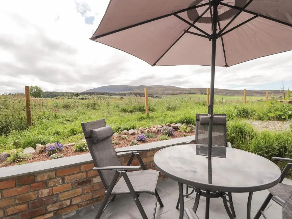 a table and chairs with an umbrella on a patio at Moss of Bourach in Aberlour