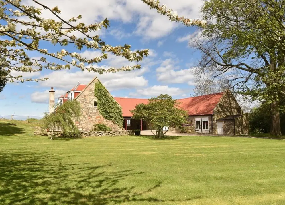 an old stone house with a red roof on a field at Gardener's Cottage in Elgin