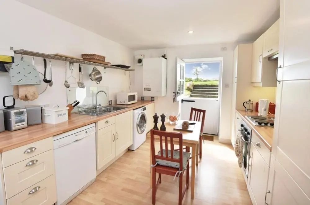 a kitchen with white cabinets and a table and chairs at Gardener's Cottage in Elgin