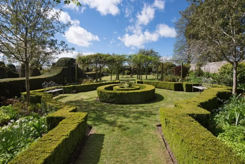 a garden with trimmed hedges and a fountain at Gardener's Cottage in Elgin