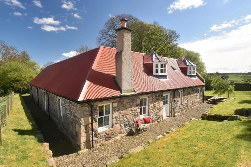 an old stone house with a red roof at Gardener's Cottage in Elgin