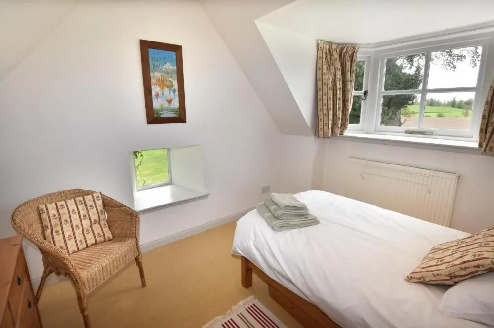 a bedroom with a bed and a chair and a window at Gardener's Cottage in Elgin