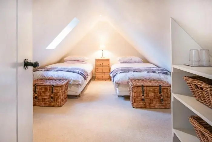 a attic bedroom with two beds and wicker baskets at Clashindeugle Farmhouse & Annex in Grantown on Spey