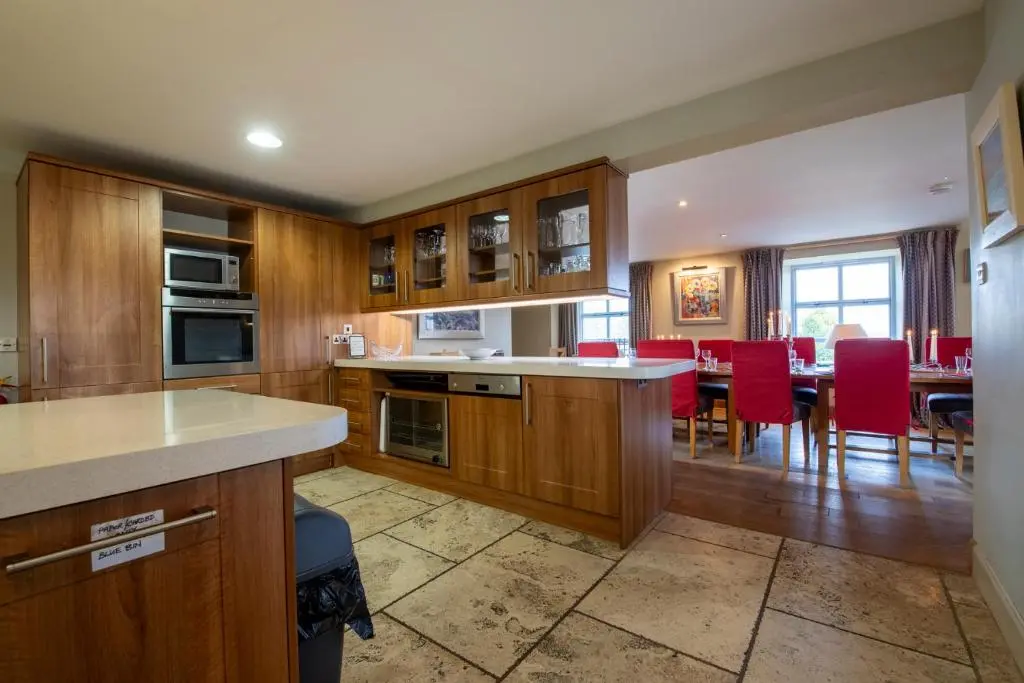 a kitchen with wooden cabinets and a table with red chairs at Quarryfield in Inverness