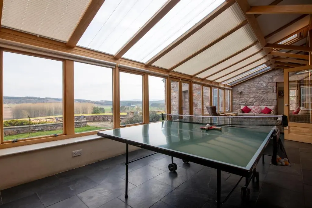a ping pong table in a room with windows at Quarryfield in Inverness
