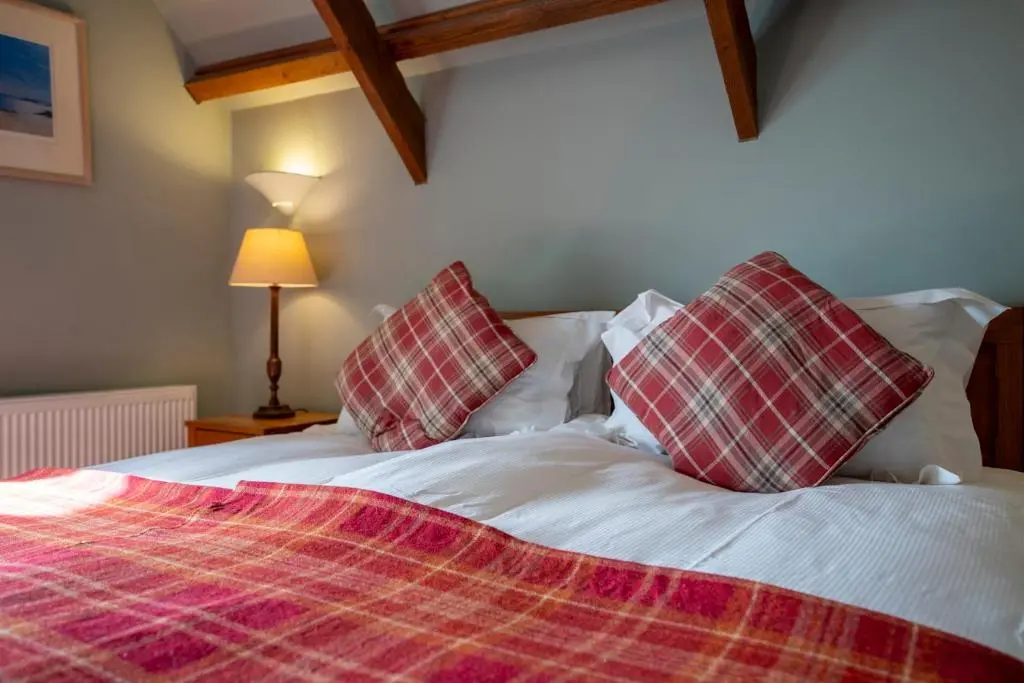 a bed with red and white plaid pillows on it at Quarryfield in Inverness