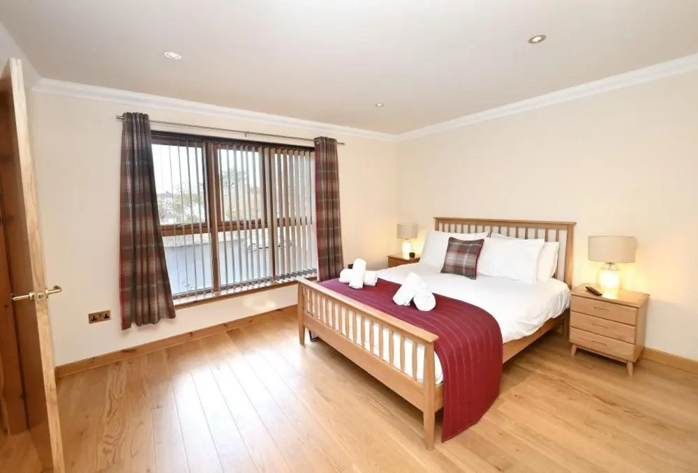 a bedroom with a large bed and a large window at Inverness City Apartment in Inverness