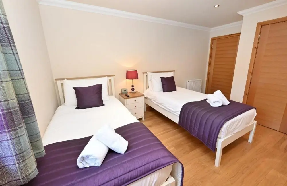 a bedroom with two beds with purple and white sheets at Inverness City Apartment in Inverness